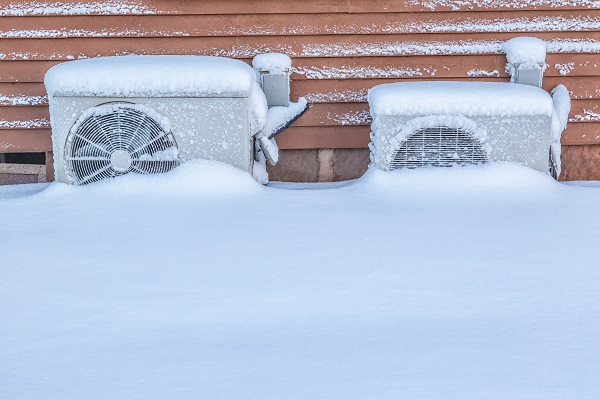 Two residential heat pumps buried in snow.